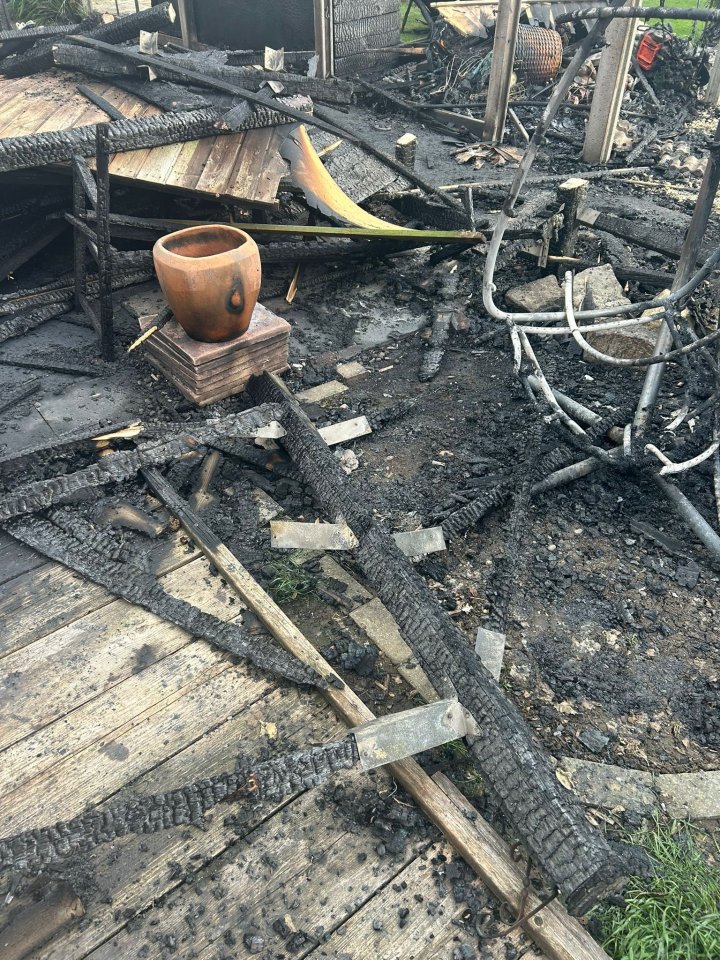 Fire damage to a garden, including charred wood and a damaged terracotta pot.