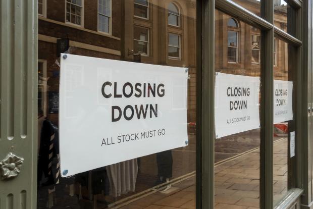 Shop window with "Closing Down, All Stock Must Go" signs.