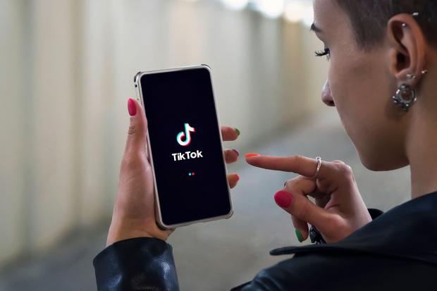 Woman using TikTok app on her phone.