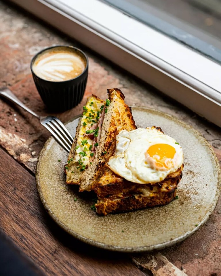 Croque monsieur with a fried egg and a cup of coffee.