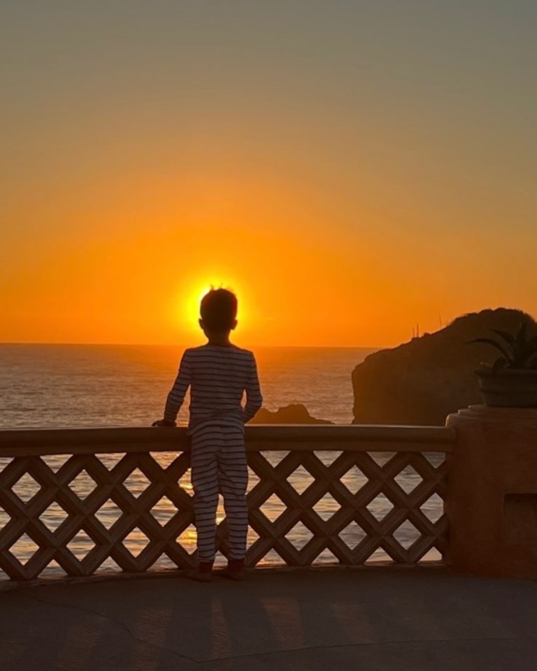Silhouette of child watching sunset over ocean.