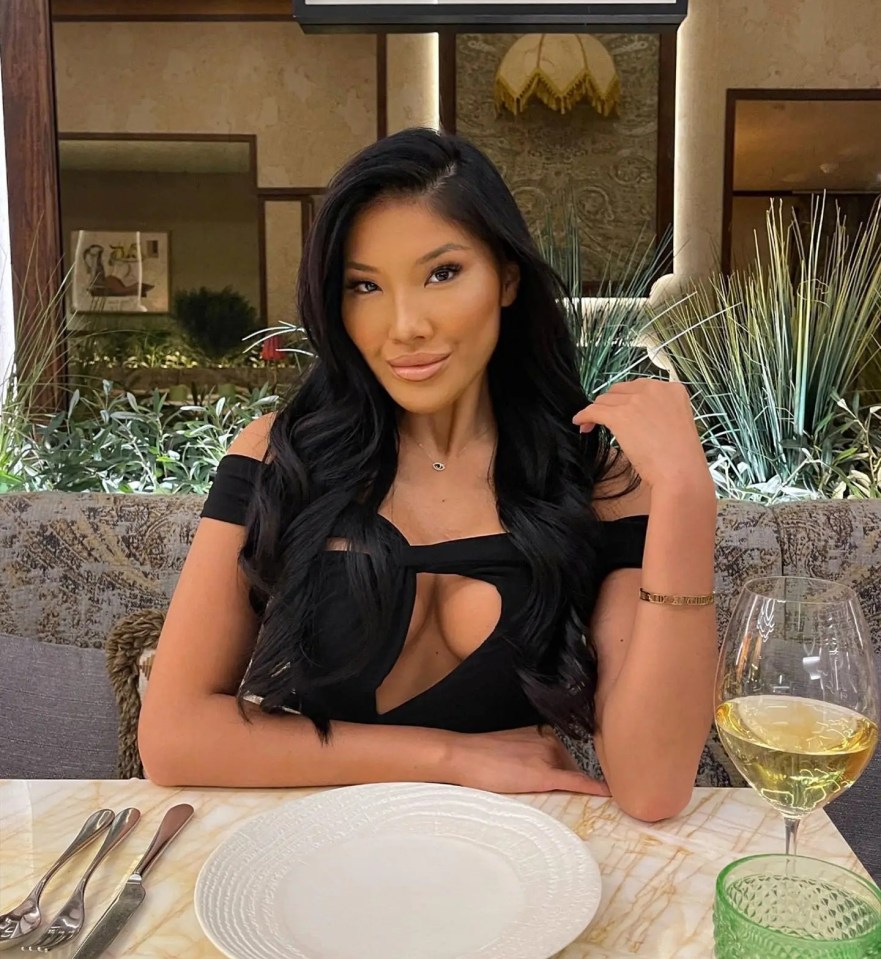 Woman in black dress sitting at a restaurant table.