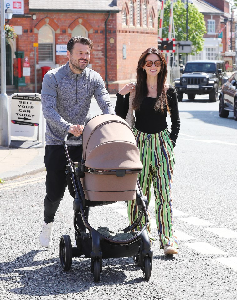 Michelle Keegan and Mark Wright pushing a baby stroller.