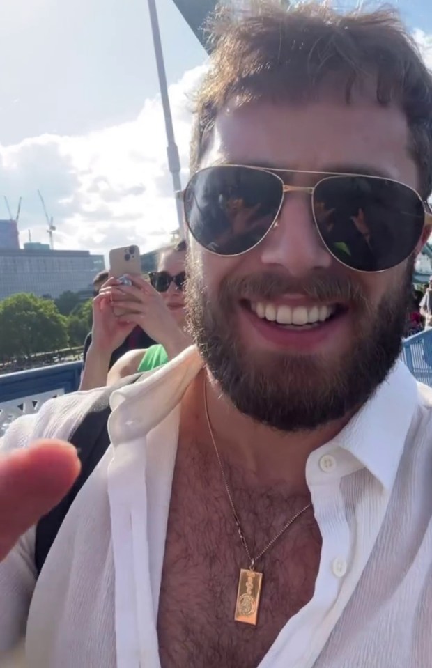Man wearing sunglasses smiles for a selfie on a bridge.