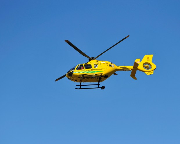 Yellow air ambulance helicopter in flight.