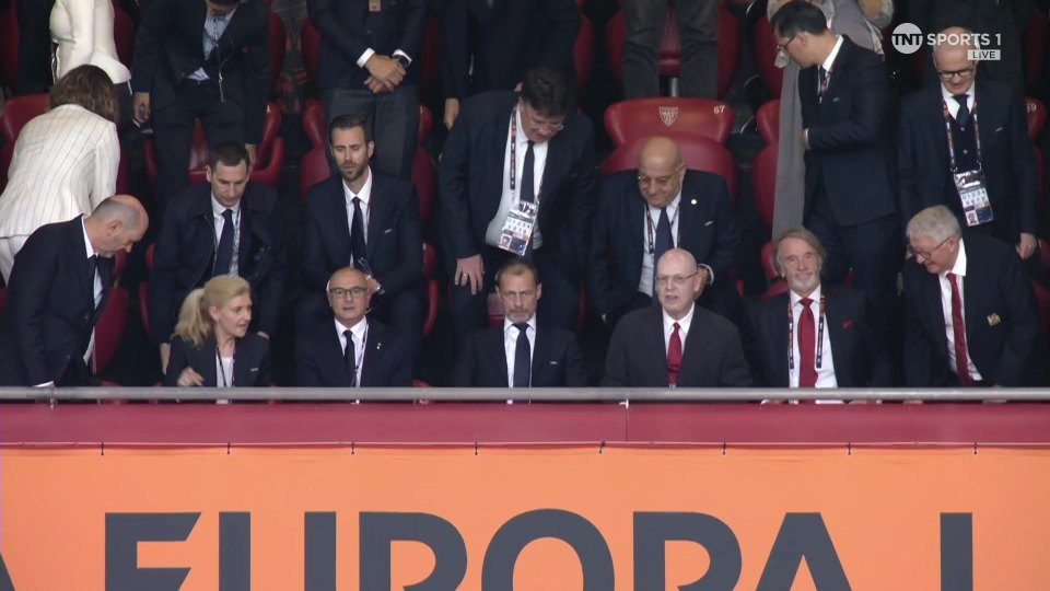 Group of people seated in stadium box seats.
