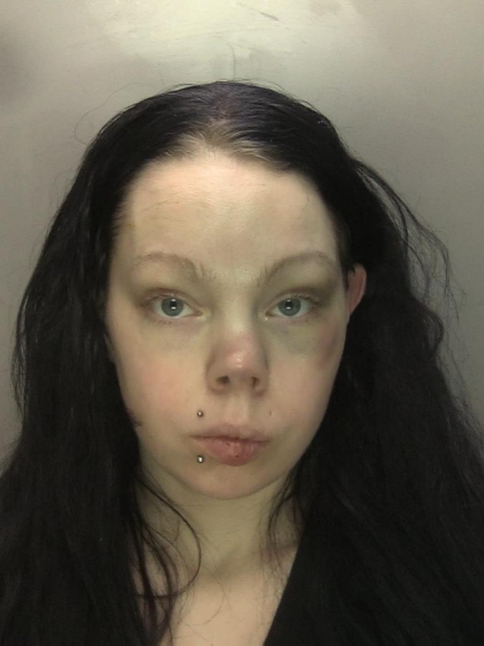 Mugshot of a woman with long dark hair and facial bruising.