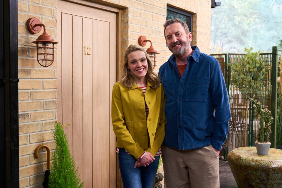A man and woman stand in front of a house.