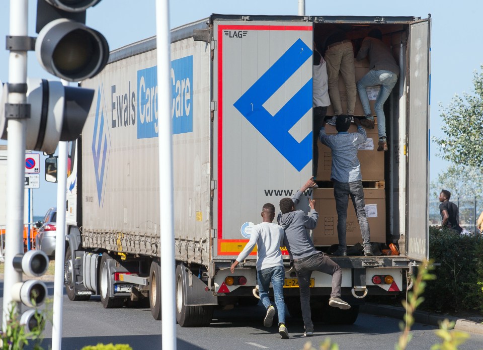 Migrants climbing into the back of a moving truck.