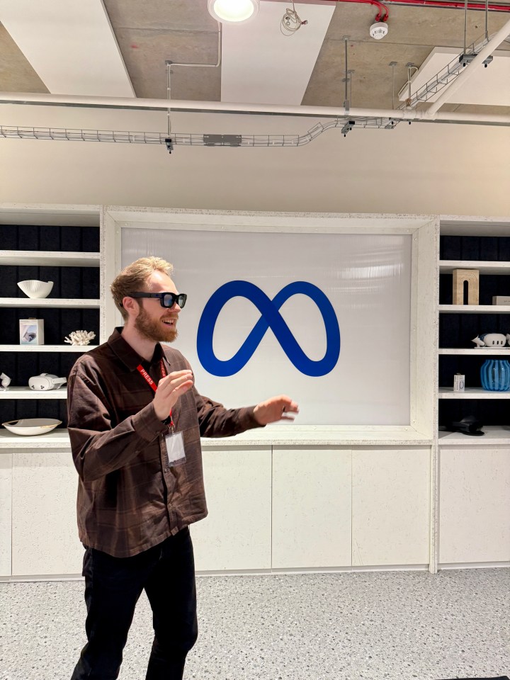 Man gesturing in front of a Meta logo.