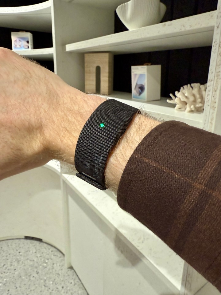 Person wearing a dark-colored wristband with a small green light.