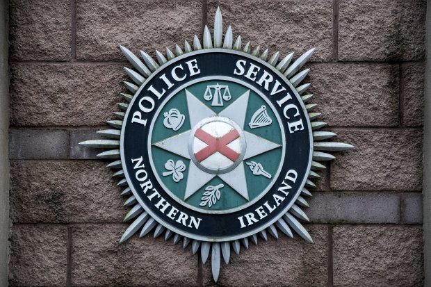 Police Service of Northern Ireland emblem on a brick wall.