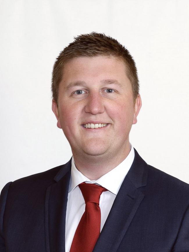 Headshot of a man in a suit and red tie.