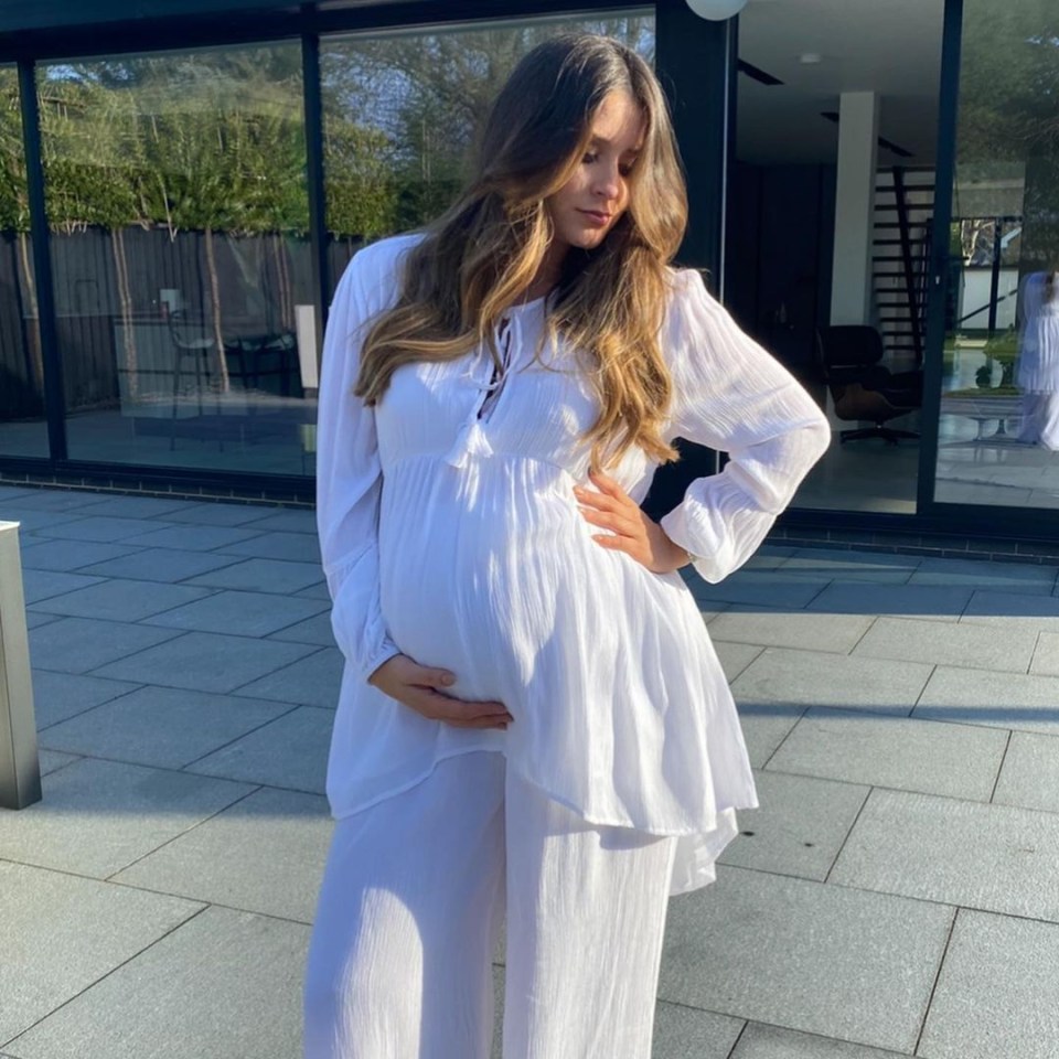 Pregnant woman in white maternity outfit.