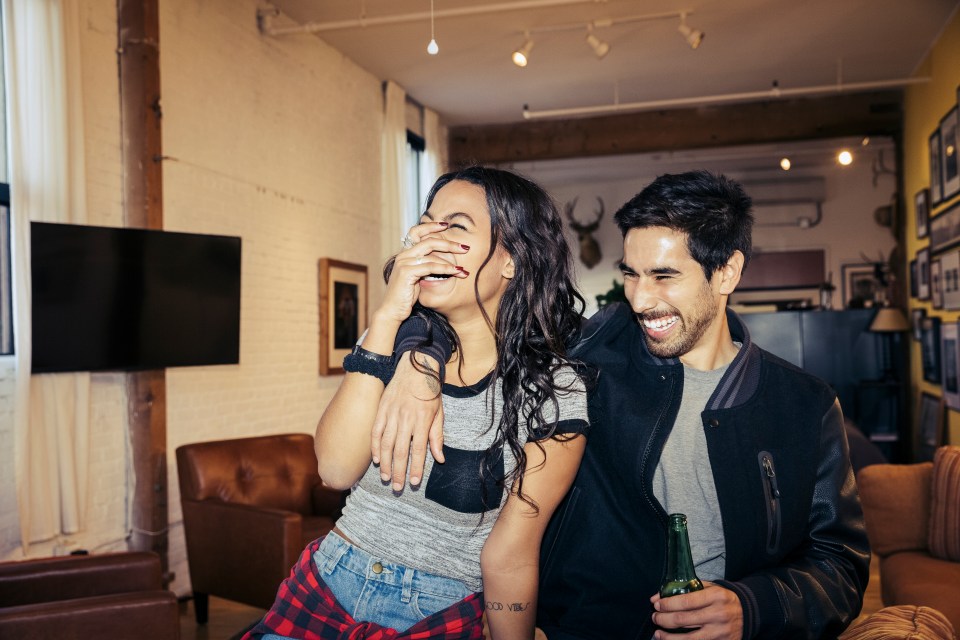 A young couple laughs together at home.