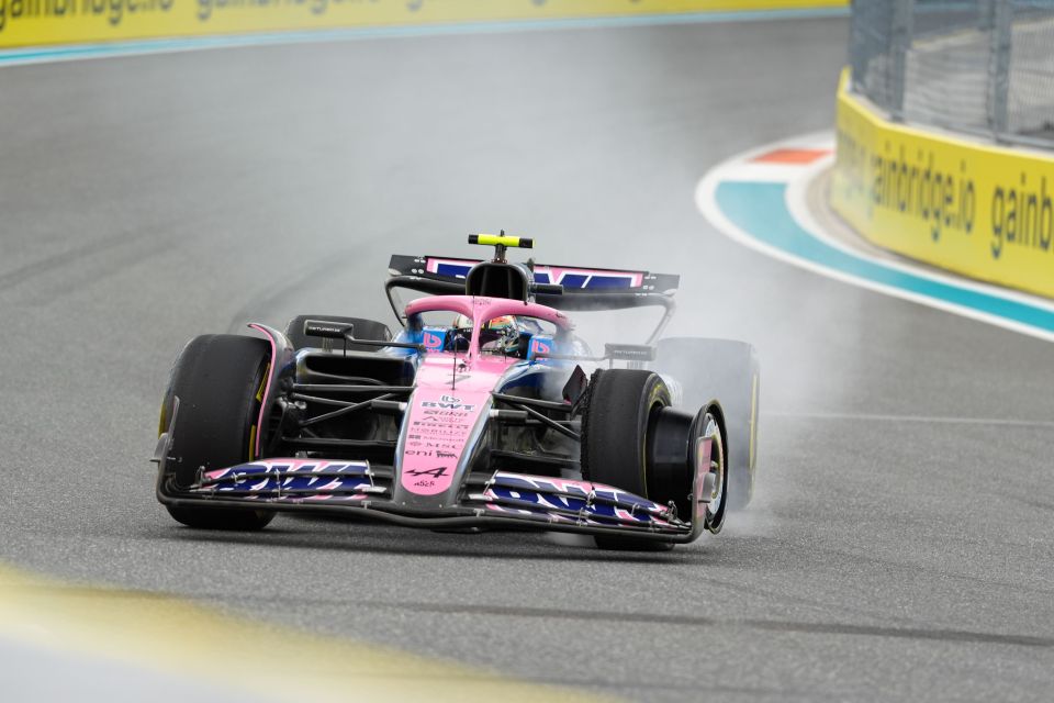 Formula 1 race car emitting smoke while driving on a track.