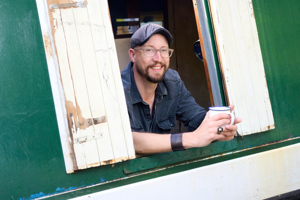 Man holding a mug, looking out a window.