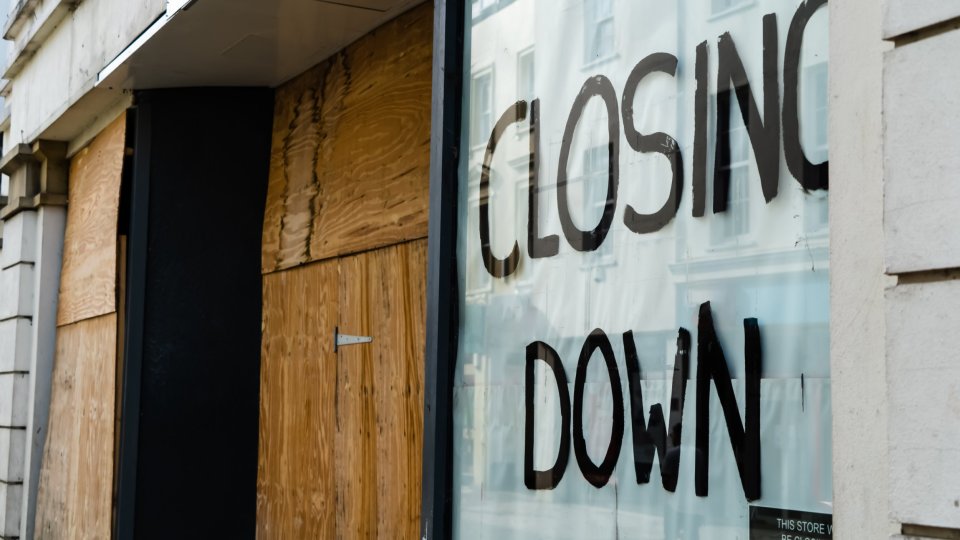 Boarded-up shop window with a "Closing Down" sign.