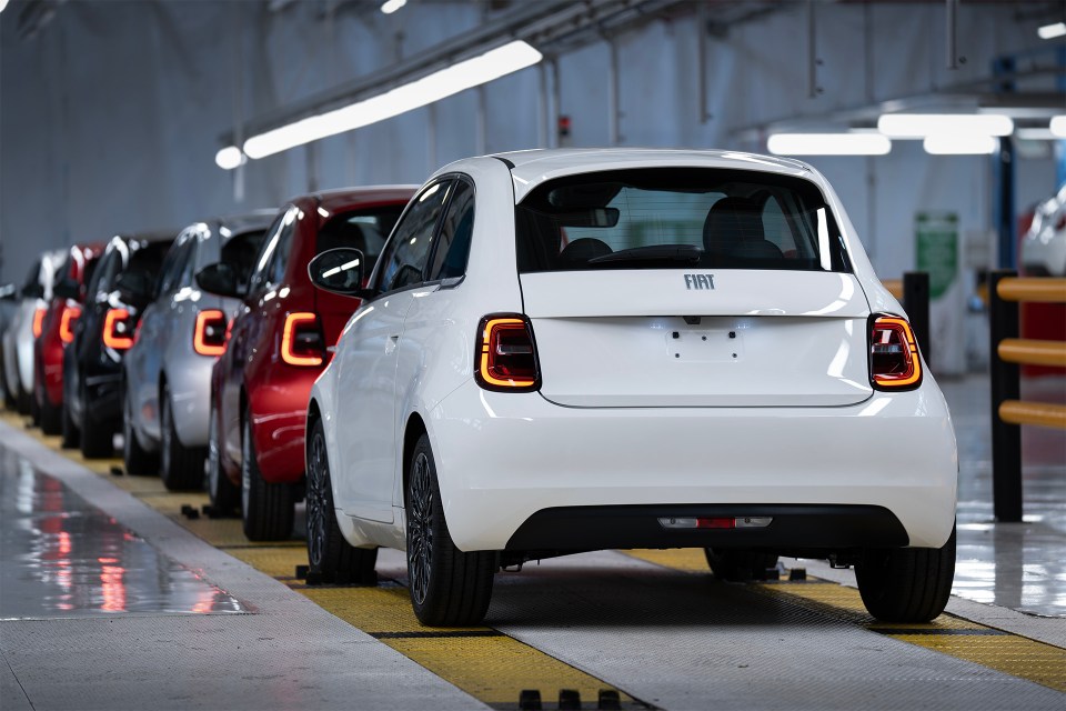 Rear view of a white Fiat 500 Hybrid on an assembly line.