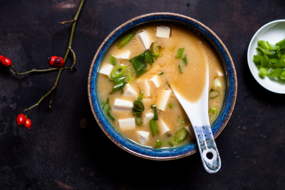 Bowl of miso soup with tofu and scallions.