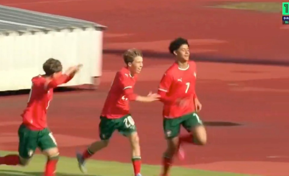 Three soccer players in red and green uniforms celebrating a goal.