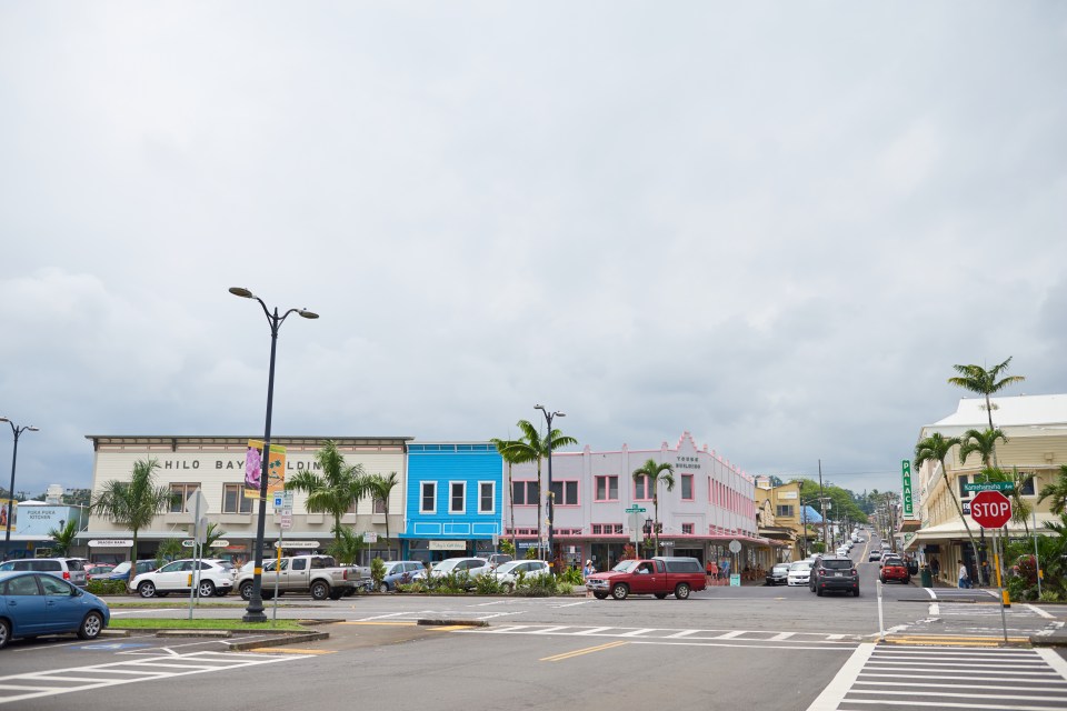 Hilo Bay street scene with shops and parked cars.