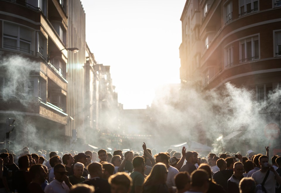 A crowd of people in a city street, with smoke or fog in the air.
