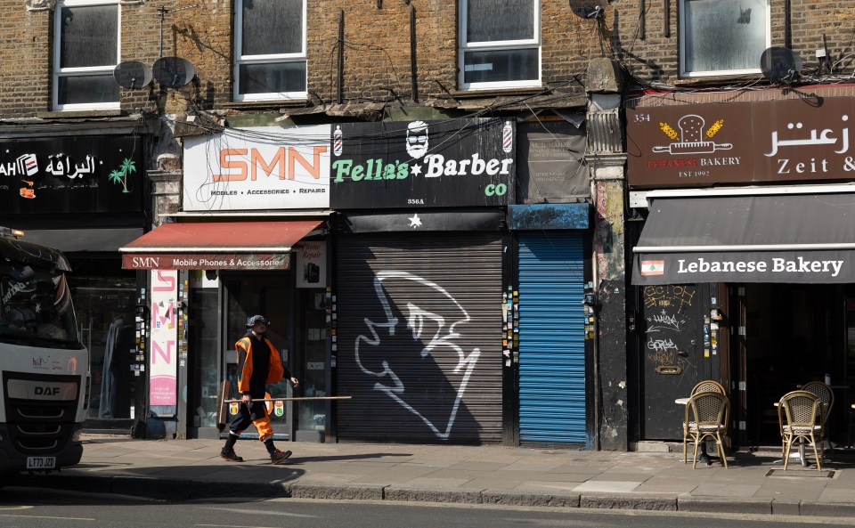 Street scene in Shepherd's Bush, London, showing several shops and a street cleaner.