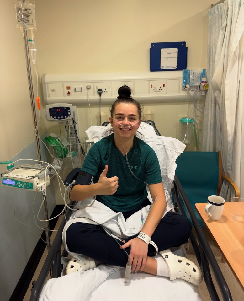 Woman in hospital bed giving thumbs up.