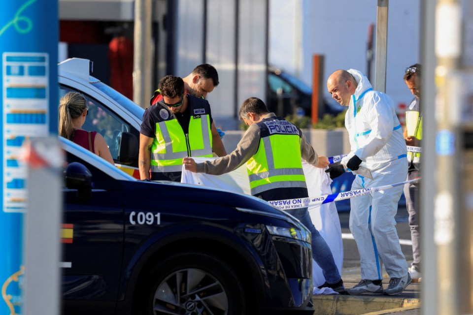 Spanish National Police officers covering a body at Gran Canaria Airport.