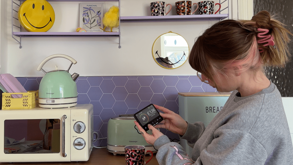 Woman checking energy usage on a smart meter in her kitchen.