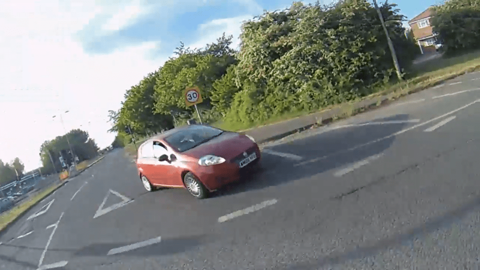 Red car turning at a 30 mph speed limit sign.