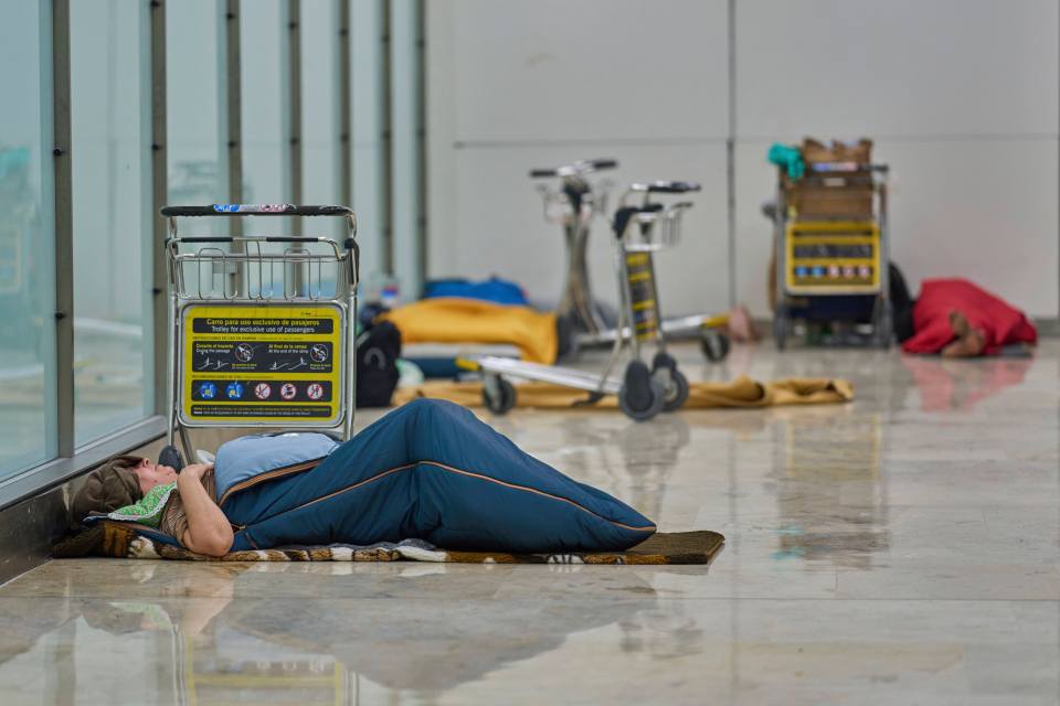Homeless people sleeping on the floor of a Madrid airport terminal.
