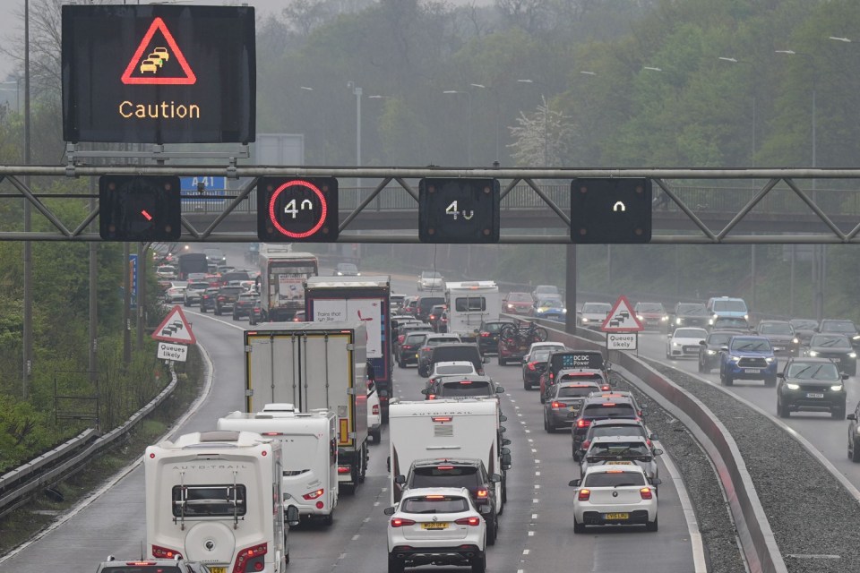 Motorway traffic jam with caution signs; delays expected.