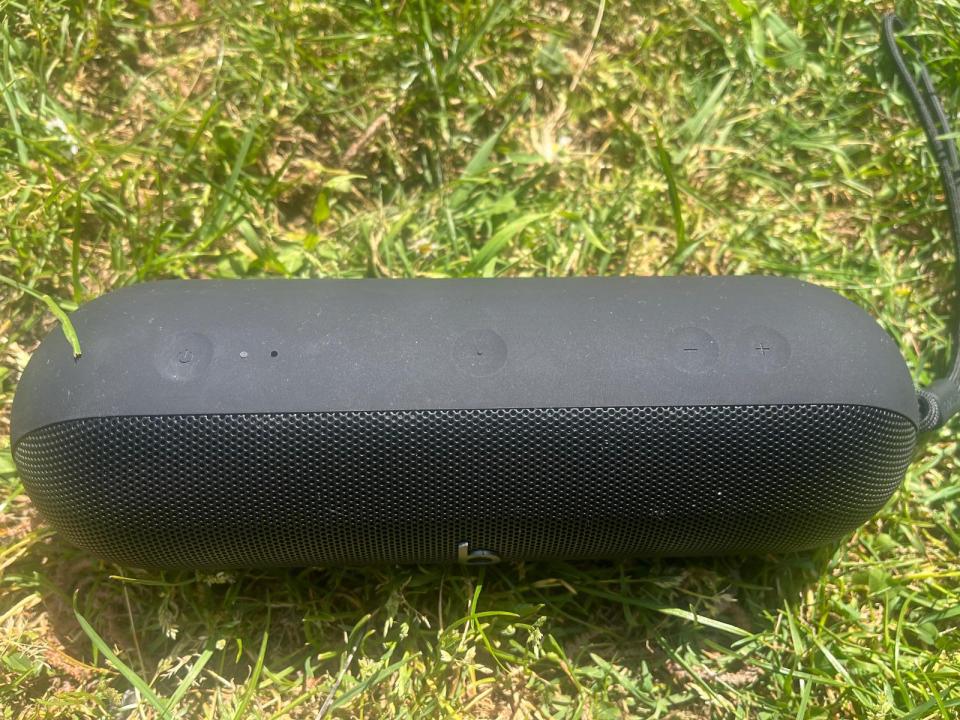 Black portable Beats Pill Bluetooth speaker on grass.