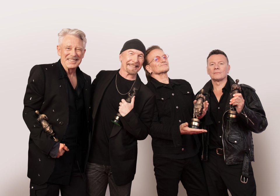 U2 band members posing with awards.