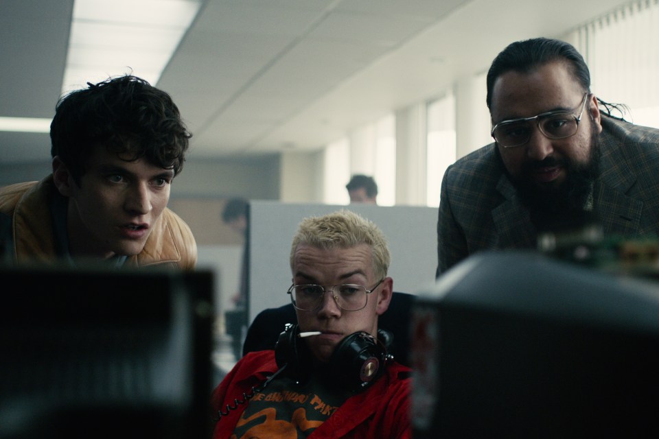 Scene from Black Mirror: Bandersnatch showing three men looking intently at a computer screen.
