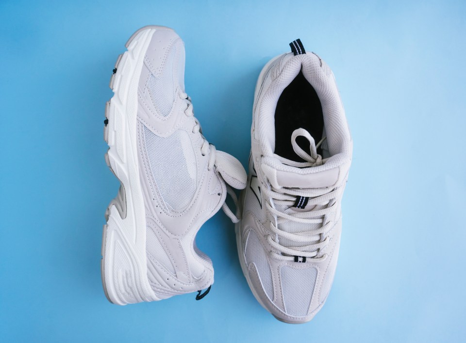 Pair of beige sneakers on a blue background.