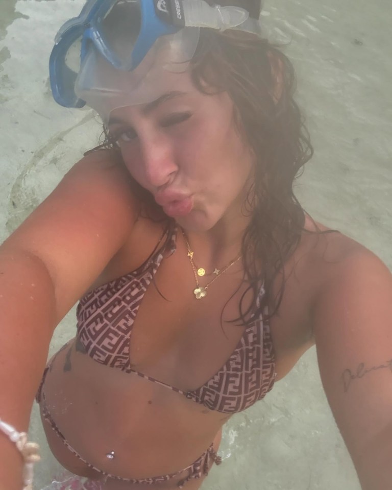 Woman in bikini and snorkel gear in shallow water.