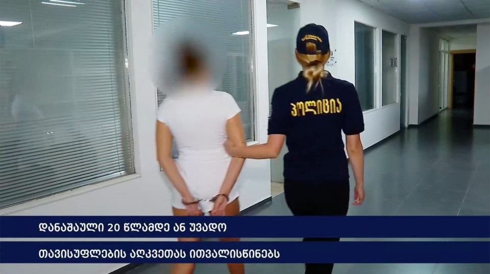 A handcuffed woman escorted by a police officer.