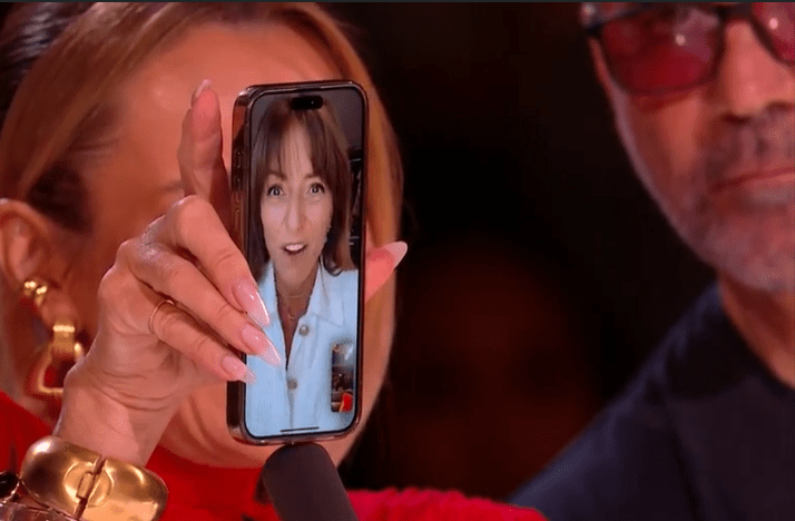 A woman holding a phone showing a video call on Britain's Got Talent.