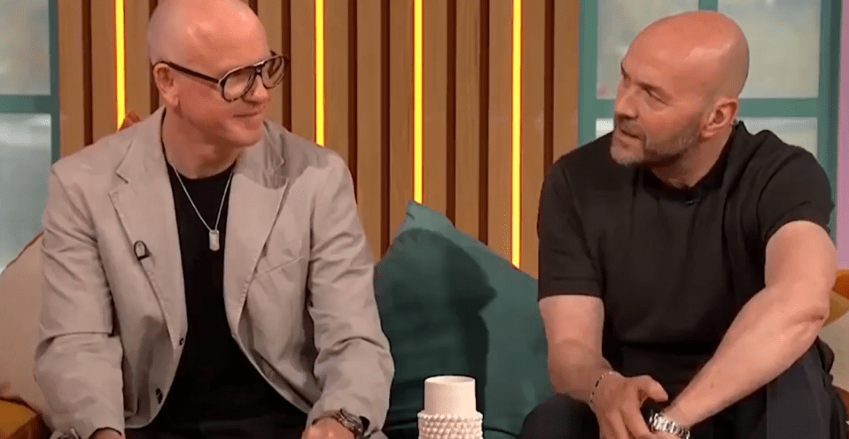 Two bald men sitting and talking on a talk show.