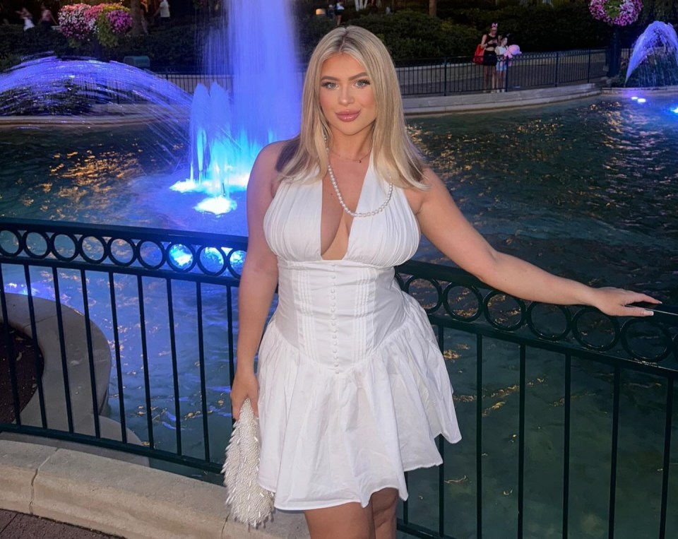 Woman in white dress by illuminated fountain.