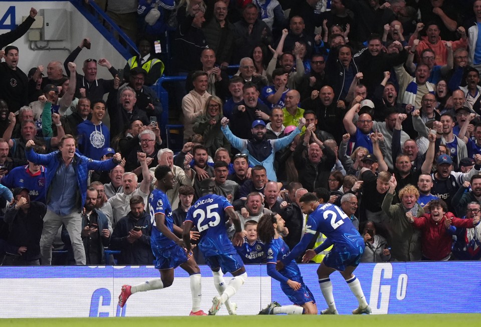 Chelsea players celebrating a goal in front of cheering fans.