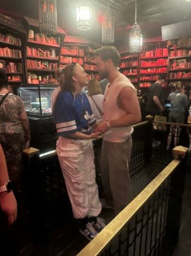 Couple standing in a room with bookshelves.