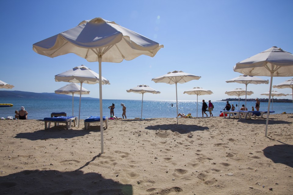 Beach umbrellas and people relaxing on a sandy beach.