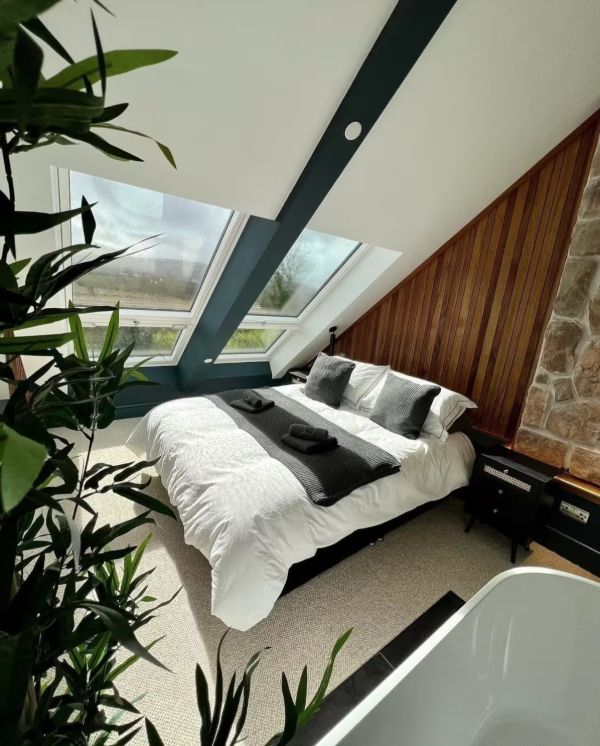 Luxury barn conversion bedroom with large windows and a freestanding bathtub.
