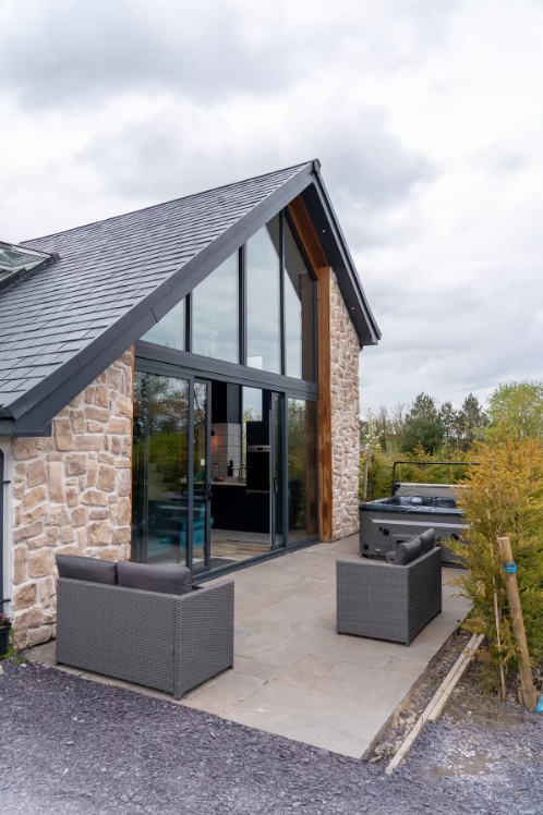 Barn conversion with large windows and hot tub.