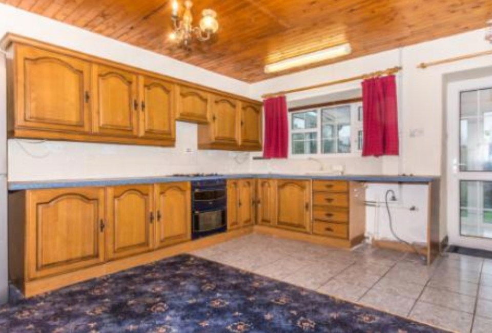 Before renovation, a kitchen with wood cabinets and a blue tiled countertop.