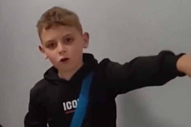 Boy in black hoodie gesturing.